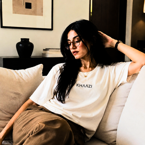 Khaazi women's white crew neck t-shirt with logo print, featuring a relaxed fit and minimalist casual design, styled in a modern studio setting.