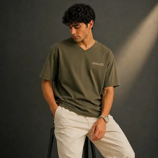 Man wearing a green t-shirt with 'KHAZI' logo against a dark background