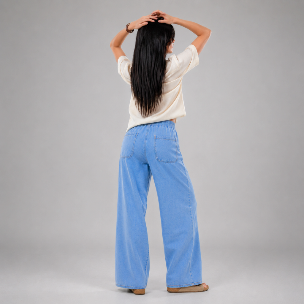 Women's light wash wide leg denim jeans with elastic drawstring waist, relaxed baggy fit, front patch pockets, and lightweight comfortable fabric, modeled in a casual fashion studio setting by Khaazi.